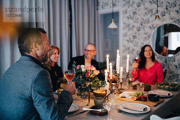 Mature friends enjoying dinner party at home