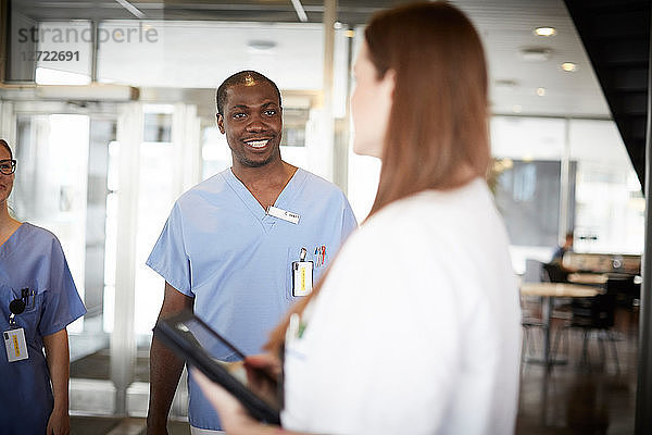 Mid adult nurses looking at young doctor standing at lobby in hospital