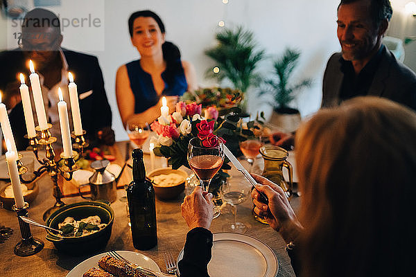 Woman raising toast with wineglass in dinner party at home