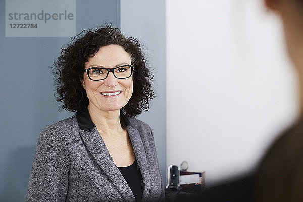 Portrait of smiling confident businesswoman wearing eyeglasses at office
