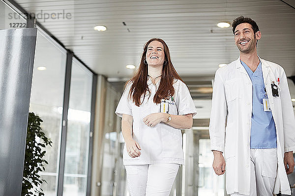 Smiling young healthcare workers looking away while walking in lobby at hospital
