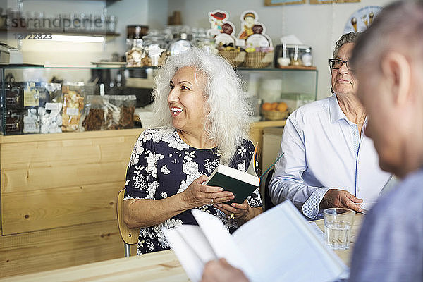 Senior man and woman with books sitting at table in coffee shop