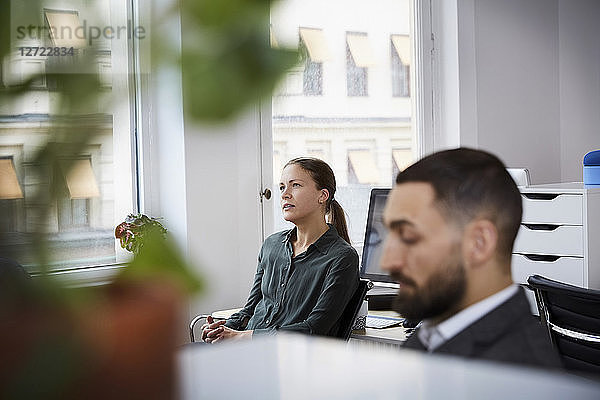 Male and female coworkers sitting in meeting at office