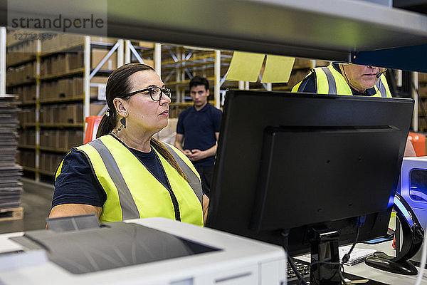 Confident mature female worker standing by coworker in distribution warehouse