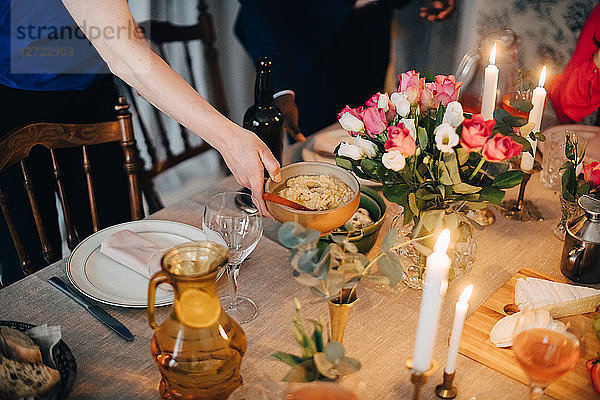 Cropped hand of woman arranging food on dining table at dinner party