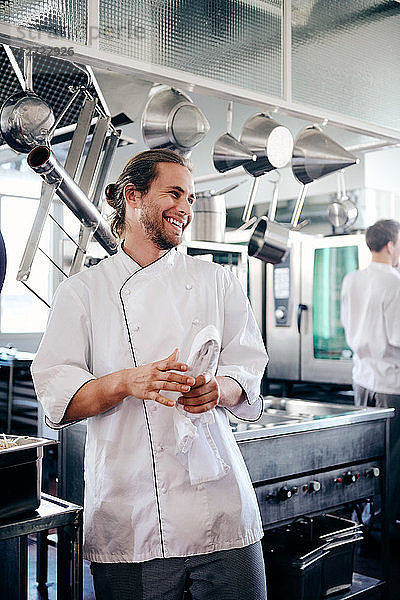Smiling male chef holding napkin in commercial kitchen