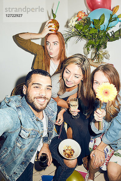 Portrait of happy young multi-ethnic friends enjoying dinner party at apartment