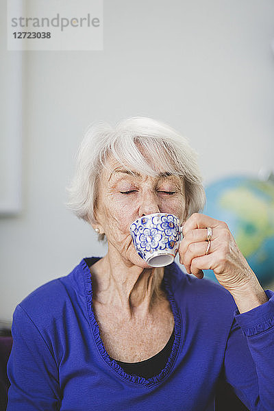 Senior woman with eyes closed having drink in nursing home