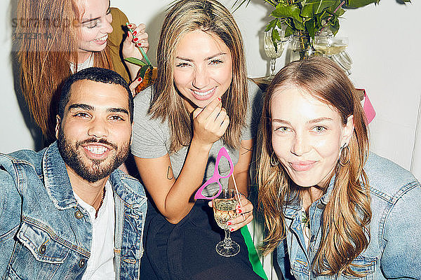 Portrait of smiling young multi-ethnic friends enjoying party at apartment