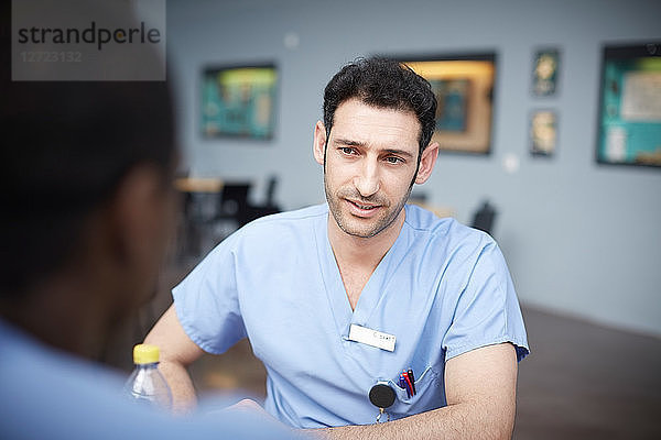 Confident male nurse talking with coworker at hospital cafeteria