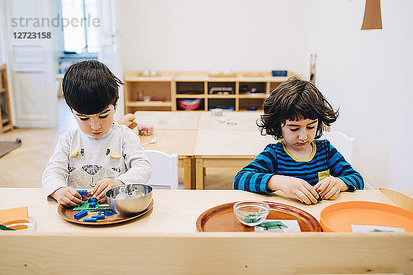 Male students playing with toys at table in child care classroom