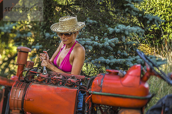 Sexy Frauen reparieren den Traktormotor auf dem Lande
