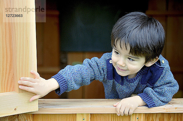 Dreijähriger kleiner Junge öffnet den Fensterladen der Hütte
