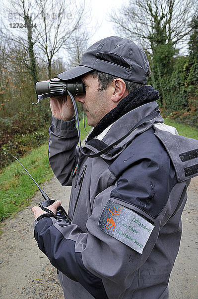Frankreich  Beamter der französischen Umweltpolitik auf Patrouille bei der Beobachtung mit einem Fernglas während einer Jagd im Departement Loire-Atlantique.