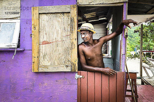 Ein junger Mann steht an der Tür seiner Hütte  Chatham Bay  Union  St-Vincent  St. Vincent und die Grenadinen  Kleine Antillen  Westindische Inseln  Inseln über dem Winde  Karibik  Mittelamerika