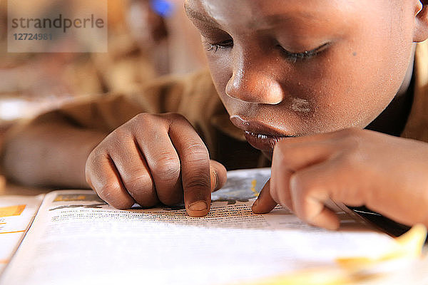 Ein togolesischer Schüler im Klassenzimmer. Lesen. Grundschule Adjalle. Lome. Togo.