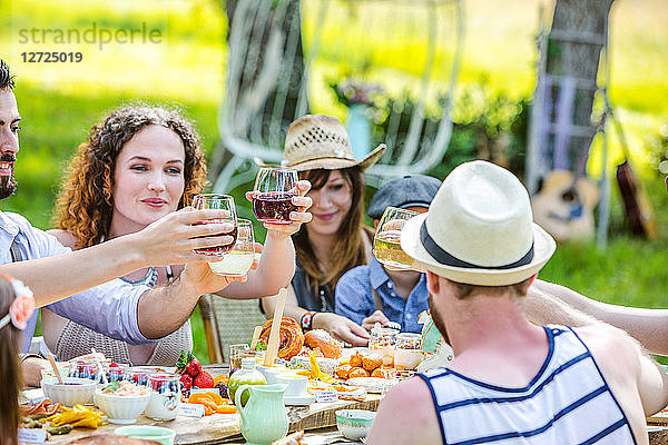 Planen Sie eine Gruppe von jungen Leuten  die bei einem Brunch auf dem Land sitzen und ihre Gläser erheben. Obligatorischer Kredit: Design culinaire : food-design-studio.fr