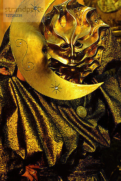 Europa  Italien  Karneval in Venedig. Goldene Sonnen- und Mondmasken. Goldenes Kleid unter dem Licht der untergehenden