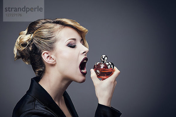 Porträt einer jungen Frau  Profil  die den Mund vor einem Parfüm öffnet