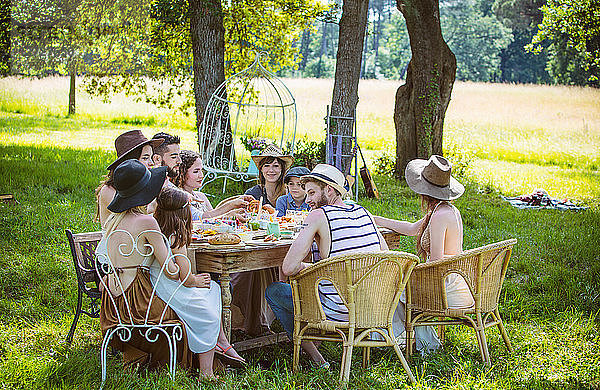 Eine Gruppe junger Leute sitzt bei einem Brunch auf dem Land. Obligatorischer Kredit: Design culinaire : food-design-studio.fr