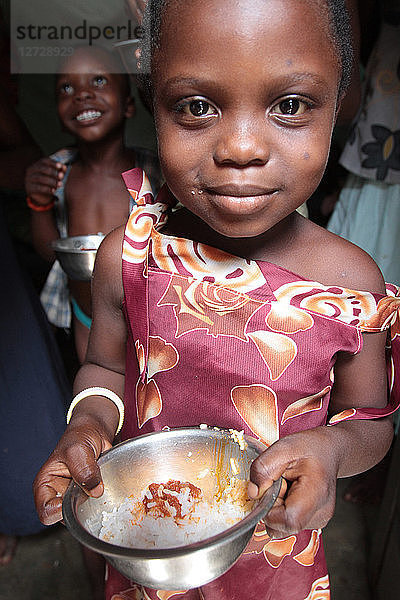Kleines togolesisches Mädchen mit einer Schüssel Reis in der Hand. Lome. Togo.