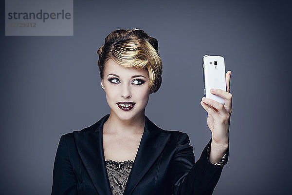 Porträt einer jungen Frau im Anzug  Vorderseite  macht ein Foto mit seinem Mobiltelefon