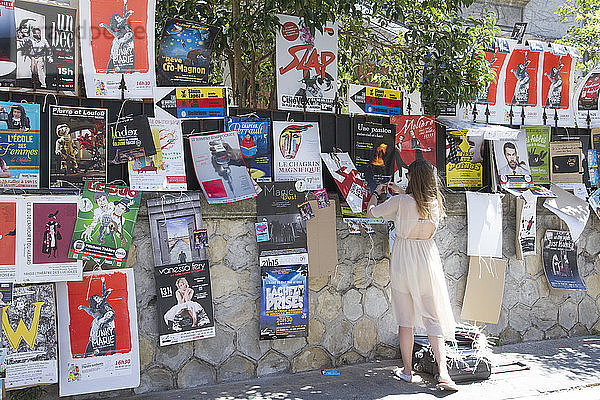 Frankreich  Vaucluse  Theaterfestival 2015  Komödiantin klebt ein Plakat für ihre Show in der Straße von Avignon