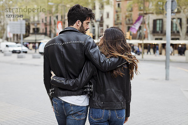 Spain  Barcelona  young couple embracing and walking in the city