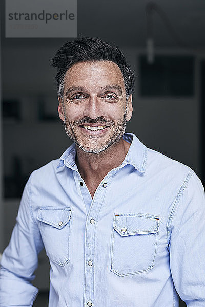 Portrait of laughing man wearing light blue denim shirt