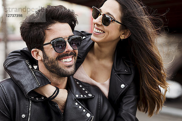 Portrait of happy young couple wearing sunglasses and leather jackets
