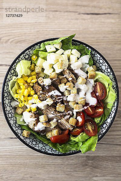 Bowl of Caesar salad with meat  corn and tomatoes