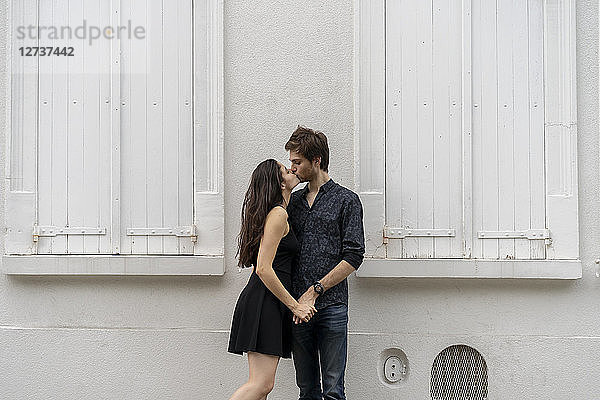 Young couple in love kissing in front of building