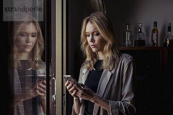 Portrait of blond young woman looking at cell phone