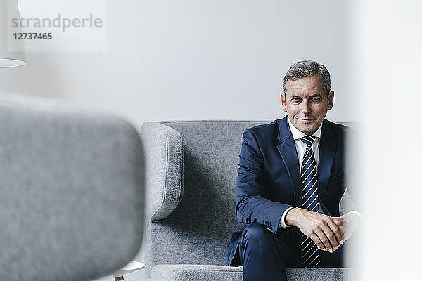 Portrait of mature businessman sitting on couch in his office