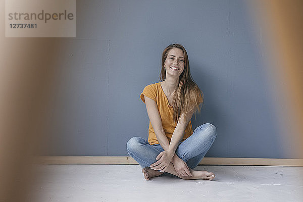 Happy woman sitting on ground  barefoot with legs crossed  laughing
