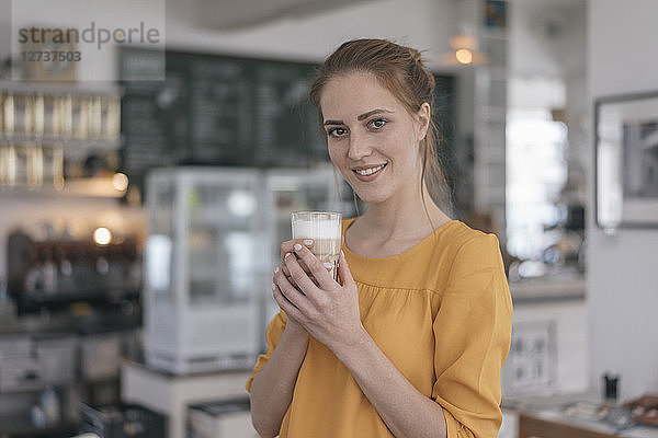 Young business owner standing in her coffee shop  drinking coffee