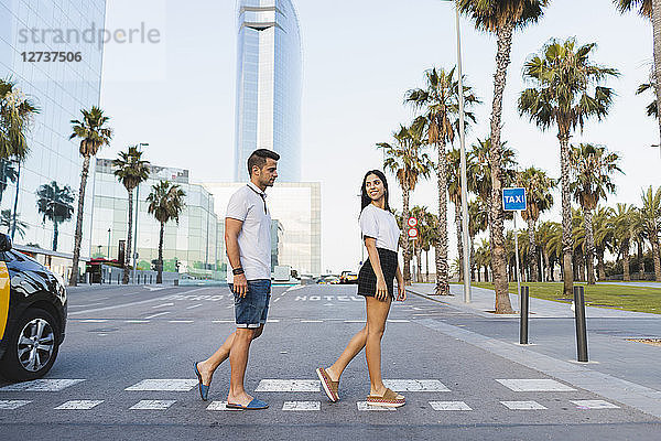 Young couple crossing street in the city  flirting