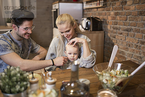 Happy young parents spending time in kitchen at home with their baby girl