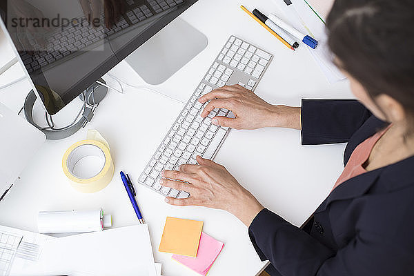 Woman using computer keyboard at desk in office