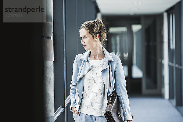 Businesswoman looking out of window in office passageway
