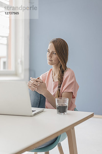 Woman at home sitting at desk with laptop