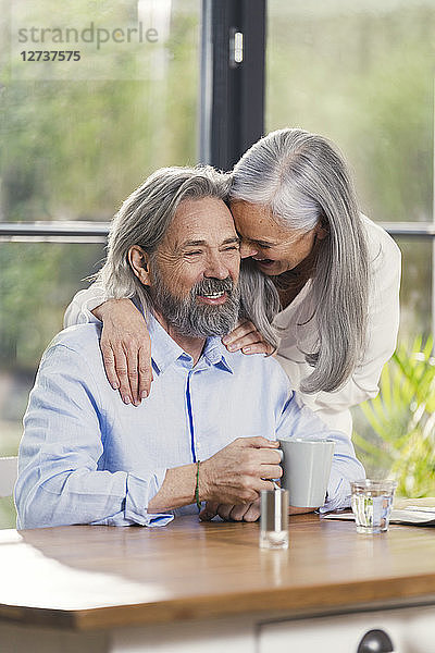 Happy senior couple drinking coffee at home