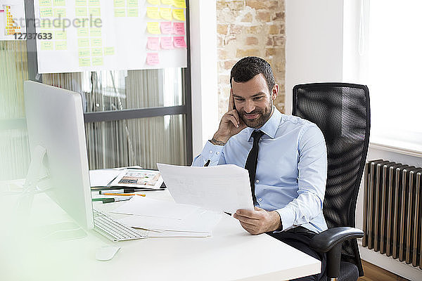 Businessman in office looking at documents at desk