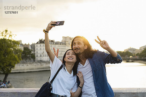 France  Paris  happy young couple taking a selfie at river Seine at sunset