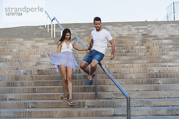 Young couple walking down stair  man sliding on railing