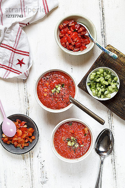 Two bowls of Gazpacho and bowls of ingredients