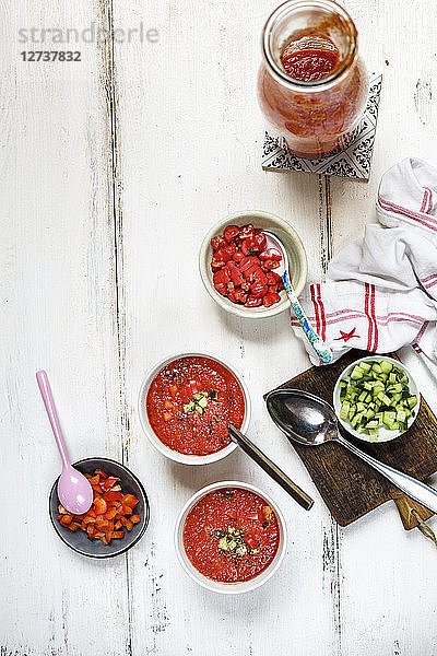 Two bowls of Gazpacho and bowls of toppings