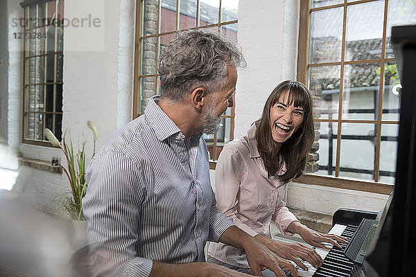 Mature couple having fun at home  playing the piano