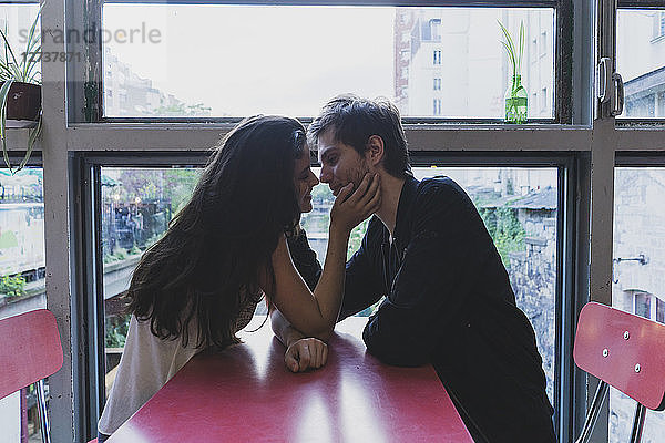 Young couple in love sitting at table at the window