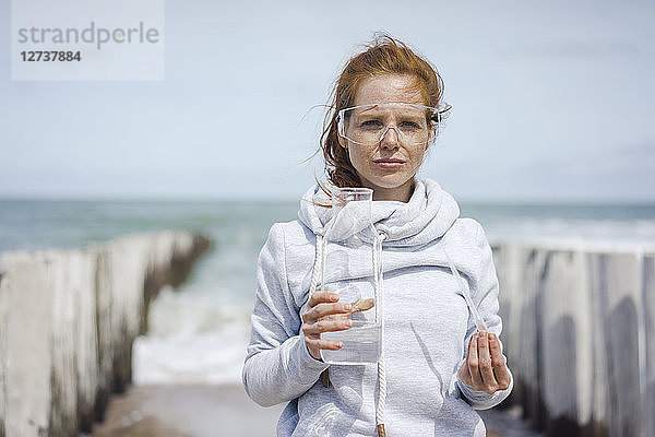 Scientist with safety glasses taking water samples at the beach